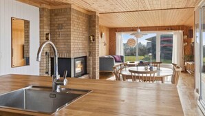 Eine moderne Küche mit Kamin aus Backstein, Holzboden und Essbereich mit Aussicht.