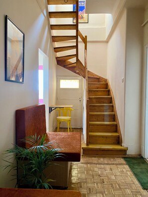 A staircase with wooden steps and a handrail, a bench, a small table, and a chair in a hallway with a door at the end. - Top floor apartment with breathtaking views, Central Cairo (Cairo Governorate)