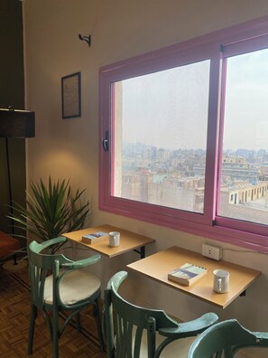 A room with two tables, two chairs, a potted plant, and a window with a view of a cityscape. - Top floor apartment with breathtaking views, Central Cairo (Cairo Governorate)