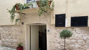 A stone building with a door, a potted plant, and a small garden area.