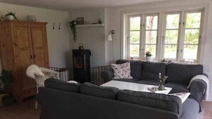 A cozy living room with a dark grey sectional sofa, a white coffee table, and a wooden cabinet. - 4 Star Holiday Home in Hadsund (Hadsund)