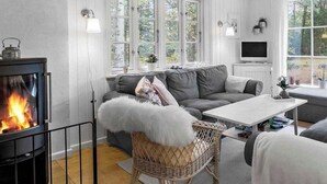 A cozy living room with a fireplace, a sofa set, a television, and large windows. - 4 Star Holiday Home in Hadsund (Hadsund)