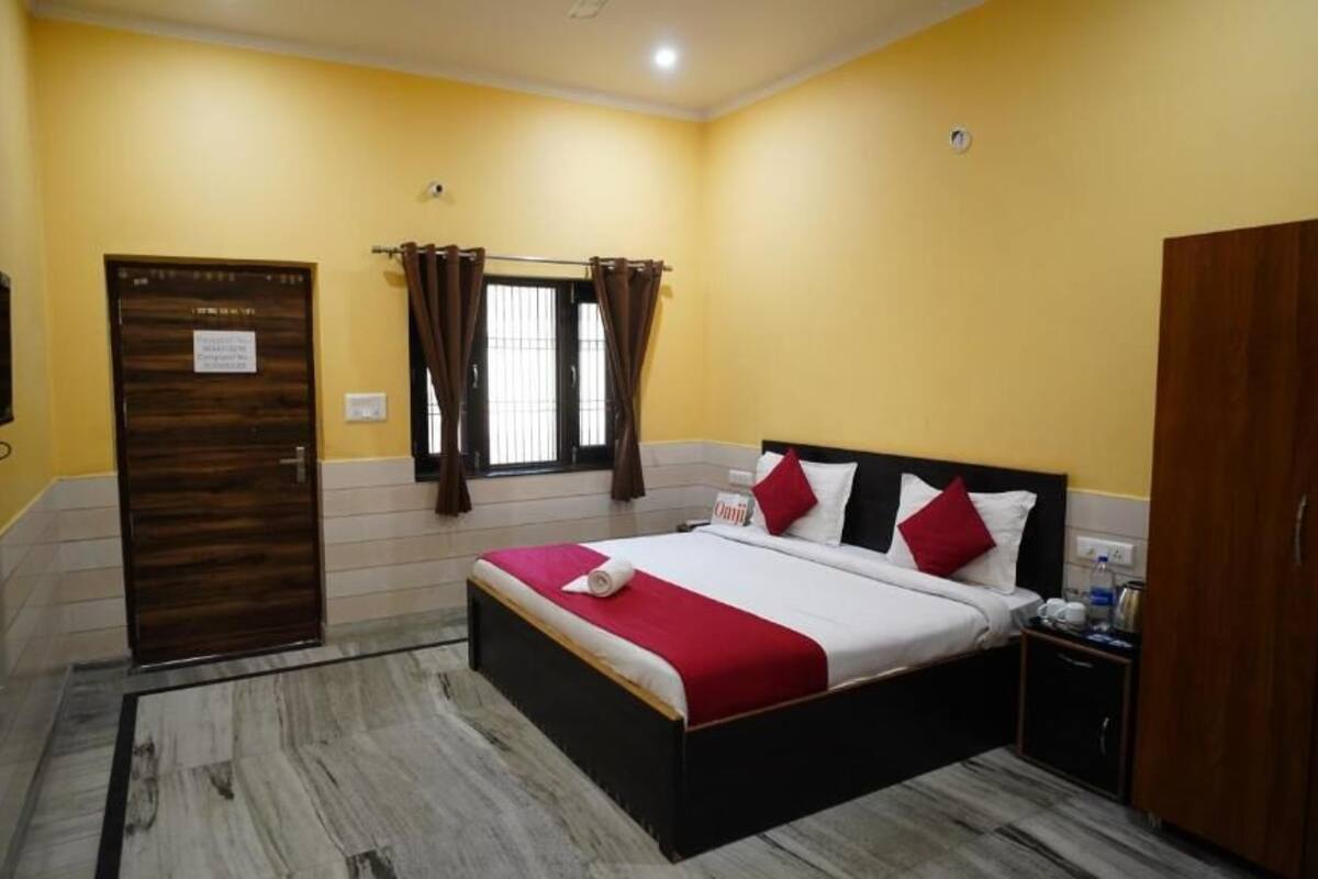 A hotel room with a bed, a wardrobe, a television, and a window with curtains.