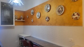Un comedor con una lámpara fijada a la pared, una mesa blanca y varias placas decorativas.