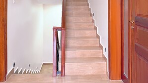 A staircase with wooden steps and a handrail, leading to a landing with a door. - Constatia Homes (Kampala)
