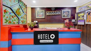 Un mostrador de recepción de hotel con un cartel que indica servicio empresarial. Hay cuadros enmarcados en la pared detrás del mostrador.