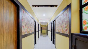 Un pasillo con papel tapiz estampado, puertas de madera y suelo de baldosas.