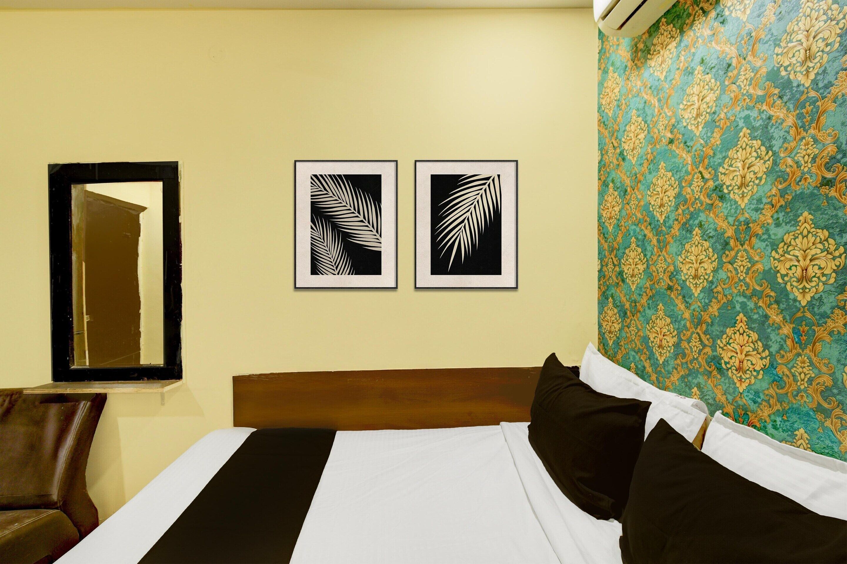 Habitación de hotel con cama, espejo, dos obras de arte con hojas enmarcadas y una pared con diseño.