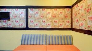 Una habitación con sofá, papel tapiz floral y televisión.
