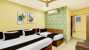 Habitación de hotel con dos camas, ventilador de techo, equipo de aire acondicionado y pared con diseño.