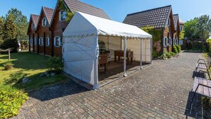 Une maison dotée d’un espace extérieur couvert, d’une allée pavée et d’un jardin.