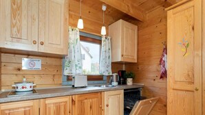 Una cucina in legno con lavastoviglie integrata, un piano cottura e una finestra con tende floreali.