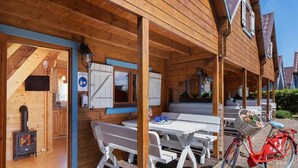 Una baita di legno con un portico coperto, un camino e una bicicletta.