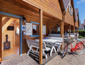 A wooden cabin with a covered patio, a fireplace, and a bicycle. - Two-story Holiday Homes With a Pool (Rewal)