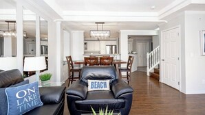Een moderne woonkamer met een leren bank, een eethoek en een keuken op de achtergrond.