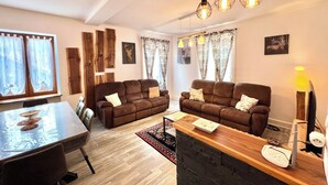 A modern living room with two sofas, a wooden reception desk, and a dining table.
