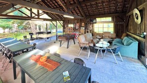 An indoor recreational area with tables, chairs, a foosball table, and a sofa.