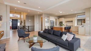 A spacious living area with a sofa, chairs, and a glass coffee table. - Bright open-concept home in Kelowna with lake views, high ceilings, fireplace. (Kelowna)
