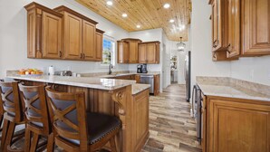 A kitchen with wooden cabinets, a marble countertop, and a wooden ceiling. - Turtle Cay Bahamas🤿Blue Marlin🛥️Marina (Green Turtle Cay)