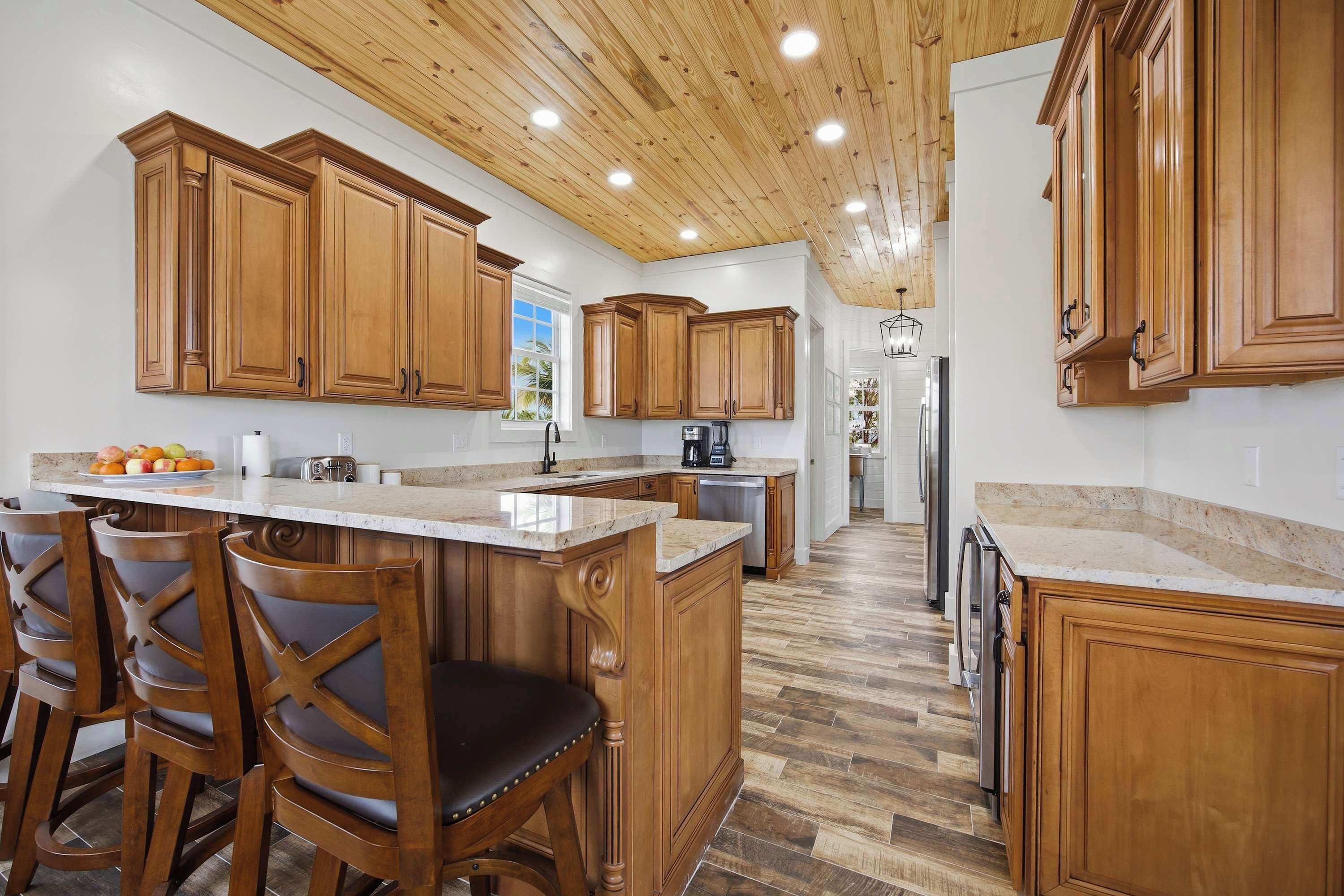 A kitchen with wooden cabinets, a marble countertop, and a wooden ceiling.