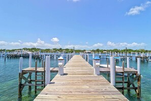 A wooden pier extending into calm waters, with multiple docks and boats visible in the background.