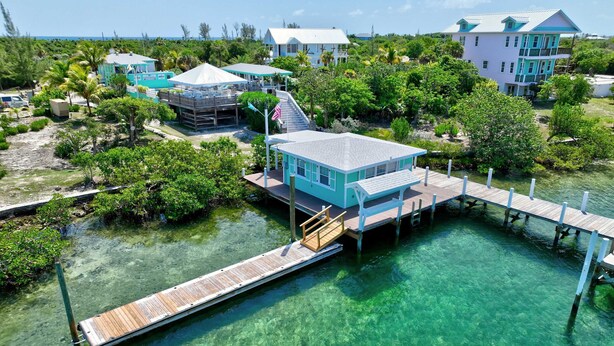 A coastal property with a dock extending into clear waters, surrounded by lush greenery and multiple buildings. - Turtle Cay Bahamas🤿Blue Marlin🛥️Marina (Green Turtle Cay)