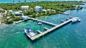 An aerial view of a coastal property with a dock, boats, and buildings surrounded by lush greenery. - Turtle Cay Bahamas🤿Blue Marlin🛥️Marina (Green Turtle Cay)