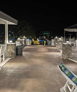 An outdoor area with stone pillars, a covered seating area, and a pathway leading to a building.