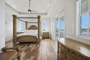 Un lit à baldaquin avec une finition en bois, une grande fenêtre offrant une belle vue et une commode en bois avec des tiroirs.