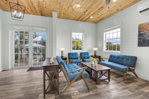 A spacious room with a wooden ceiling, large windows, and a blue sofa set.