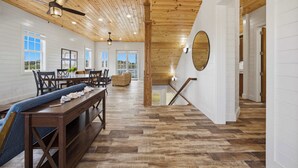 A spacious dining area with wooden flooring, a long table, and chairs. There are windows providing natural light and a view of the outdoors. - Turtle Cay Bahamas🤿Blue Marlin🛥️Marina (Green Turtle Cay)