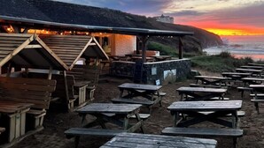 A beachside restaurant with outdoor seating and a view of the sunset over the ocean. - River View Cottage in the heart of the beautiful Cornish village of Gweek (Gweek)