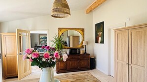 A room with a wooden table, a vase of flowers, a hanging light fixture, a mirror, and wooden cabinets. - River View Cottage in the heart of the beautiful Cornish village of Gweek (Gweek)
