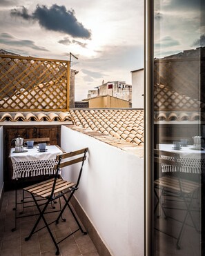 Ein Balkon mit Tisch, Stühlen und Blick auf Gebäude.