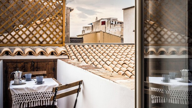 Un balcone con tavolo, sedie e vista sugli edifici.