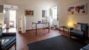 Un soggiorno con divano, tavolo da pranzo con sedie, lampada e una mappa del mondo appesa al muro.