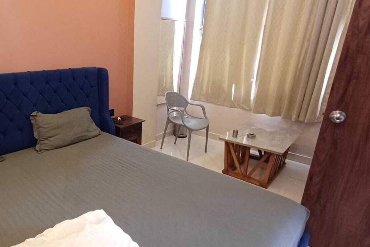 Un dormitorio con una cama grande, una mesita de noche, una silla y una pequeña mesa.