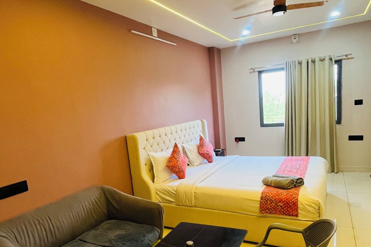 Una habitación de hotel moderna con cama, sofá, mesa de comedor, sillas y un ventilador de techo.