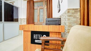 A hotel reception desk with a wooden counter, a sign indicating 'HOTEL,' and a stone wall in the background. - Deluxe Dream Stay Hotel (Lucknow)