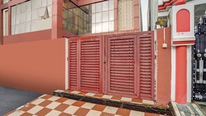A red gate with a checkered floor leading to a building with a red and white facade. - Deluxe Dream Stay Hotel (Lucknow)