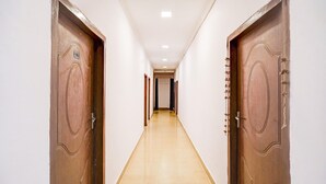 A corridor with two wooden doors on either side, a light-colored floor, and a ceiling with recessed lighting. - Deluxe Dream Stay Hotel (Lucknow)