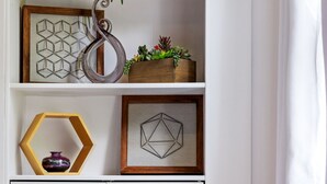 Un armario blanco con espejo, una planta colgante y repisas hexagonales con objetos decorativos.