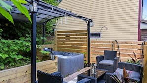 A patio area with outdoor furniture, a hot tub, and a pergola structure. - 2 King Beds w Hot Tub Near Butler St (Pittsburgh)