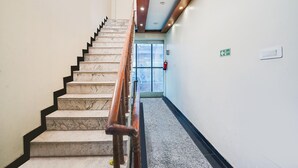 Eine Marmortreppe mit hölzernen Geländern führt zu einem Eingang mit Glastür und einem Ausgangsschild.