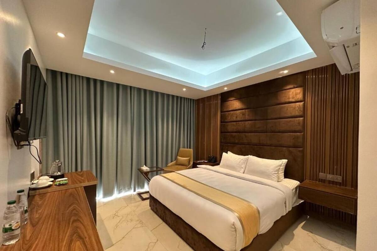 Een moderne hotelkamer met een groot bed, een bureau met stoel, een televisie en een plafondlamp.