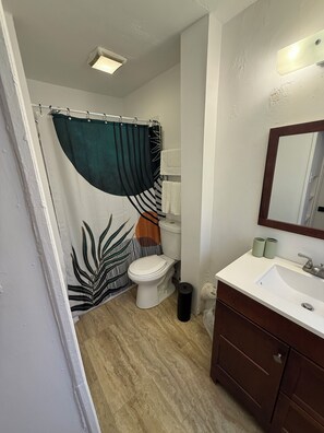 Un baño con inodoro, lavamanos, espejo y cortina de ducha.