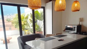 A modern kitchen with a white island, black chairs, and a view of the city through large windows. - Serene 2-bedroom apartment in Medellín perfect for your getaway . Amaizing view (barrio santa fe medellin)