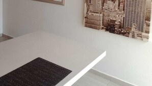 A dining area with a white table, a woven pendant light, a framed mirror, and a cityscape mural. - Serene 2-bedroom apartment in Medellín perfect for your getaway . Amaizing view (barrio santa fe medellin)