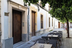 A row of outdoor tables and chairs, a wooden door, and a building facade with a number plaque. - Córdoba Center Monumental Home (Cordoba)