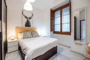 A bedroom with a bed, nightstands, a lamp, a wall-mounted artwork of a deer, and a window with curtains. - Córdoba Center Monumental Home (Cordoba)